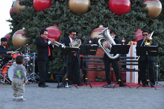 Criança escuta atentamente à banda em frente a árvore de natal gigante na Cidade da Guatemala, capital do país